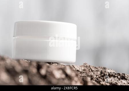 white cosmetic jar on tree bark Stock Photo