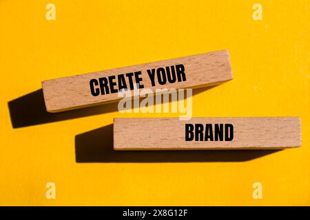 Create your brand words written on wooden blocks with yellow background. Conceptual create your brand symbol. Copy space. Stock Photo