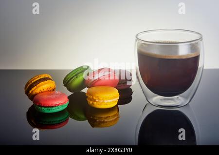 A cup of coffee sits on the table, accompanied by a variety of colorful macarons. The food and drinkware create a delightful display of ingredients in Stock Photo