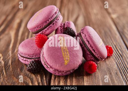 A delightful pile of purple macarons with chocolate and berries arranged on a wooden table, showcasing the perfect combination of sweet ingredients an Stock Photo