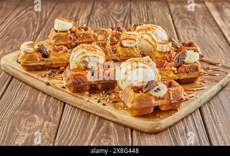 A delicious assortment of donuts, a popular baked good and staple food in American cuisine, is stacked on a wooden table. These sweet confectioneries Stock Photo
