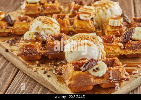 A delicious assortment of donuts, a popular baked good and staple food in American cuisine, is stacked on a wooden table. These sweet confectioneries Stock Photo