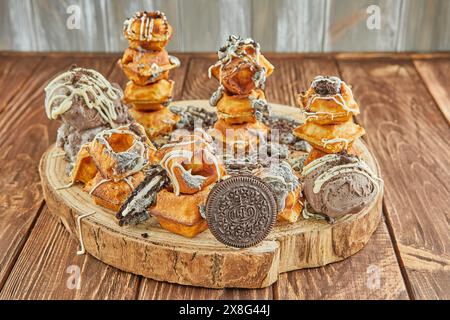 A delicious assortment of donuts, a popular baked good and staple food in American cuisine, is stacked on a wooden table. These sweet confectioneries Stock Photo