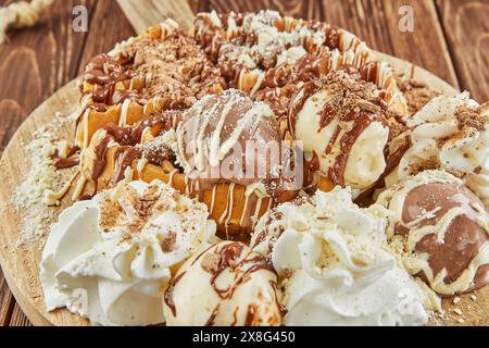 A delicious assortment of donuts, a popular baked good and staple food in American cuisine, is stacked on a wooden table. These sweet confectioneries Stock Photo