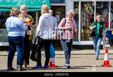 Women meeting on Framlingham's Market Hill for a sunny Tuesday street market, a sociable occasion for chatting and exchanging  news. Stock Photo