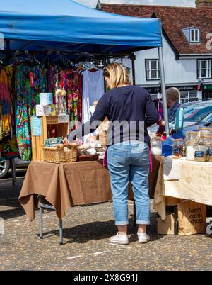 A sunny day for the twice weekly street market in Framlingham Suffolk with colourful ethically sourced women's clothing offered for sale Stock Photo