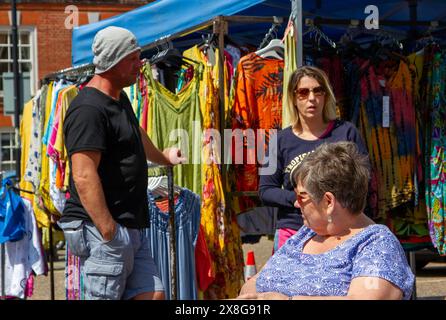 A sunny day for the twice weekly street market in Framlingham Suffolk with colourful ethically sourced women's clothing offered for sale Stock Photo