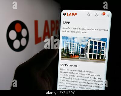 Person holding cellphone with webpage of German cable company Lapp Holding SE in front of business logo. Focus on center of phone display. Stock Photo
