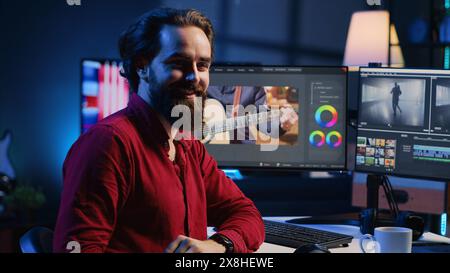 Happy videographer reviewing footage and selecting scenes, trimming them using specialized software applications and editing tools. Smiling video editor working for media company in editing room Stock Photo