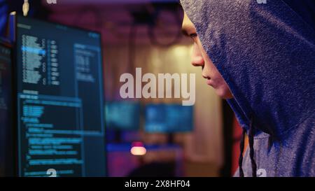 Extreme close up on hacker in graffiti painted hideout focused on developing spyware software, using it to gather information from users computers without their knowledge Stock Photo