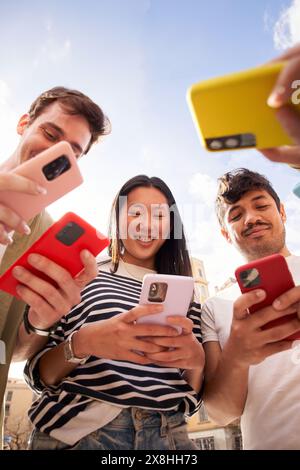 Low angle view multiracial group young generation z in circle using phones together outdoors. Stock Photo