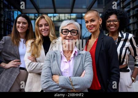 Portrait group formal business women of different ages looking smiling at camera together outdoors.  Stock Photo