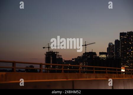 Evening skyline - construction cranes silhouette against fading light - urban development. Taken in Toronto, Canada. Stock Photo