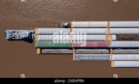 A towboat, known as a pusher, pushes barges full of cargo up the Mississippi River near downtown Baton Rouge, Louisiana, USA. Stock Photo