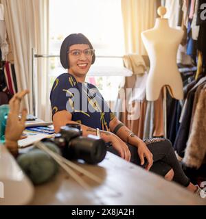 Portrait, woman and fashion designer in atelier with smile as stylist for company or customer as entrepreneur. Female person, tailor and workshop for Stock Photo