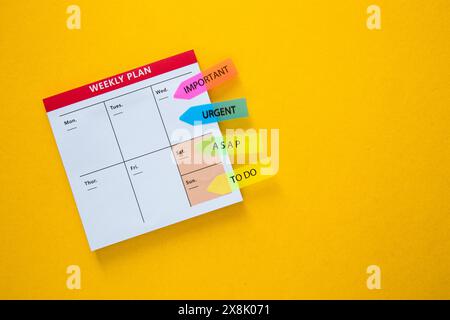 White weekly plan on a yellow background with bright colored sticky notes for organization Stock Photo