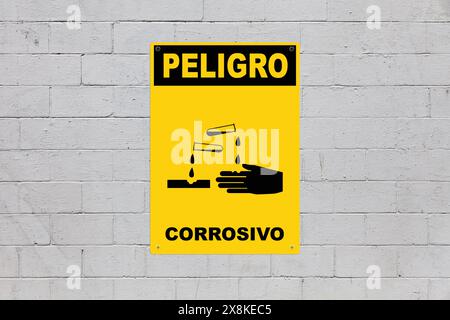 Yellow warning sign screwed to a brick wall to warn about a threat. In the middle of the panel, there is a gas mask symbol and the message in Spanish Stock Photo