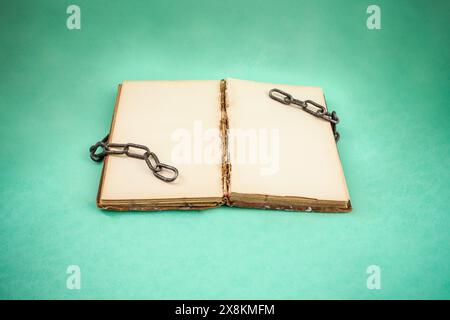 Open book with empty yellowed pages and broken chains in green  background, freedom of speech in literature concept Stock Photo