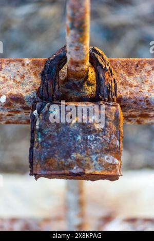 Rusty Weathered Iron Padlock in Close-up View Surrounded by Outdoor Industrial Elements Stock Photo