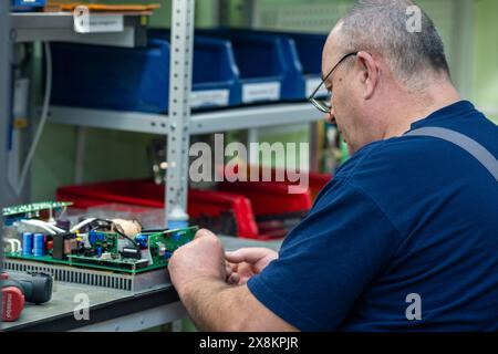 Perm, Russia - May 23, 2024: male worker assembling electronic equipment in a workshop Stock Photo