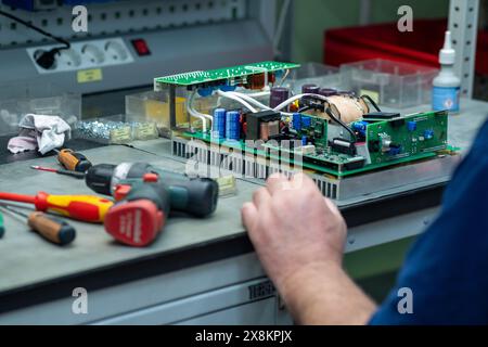 Perm, Russia - May 23, 2024: worker assembling electronic equipment in a workshop Stock Photo