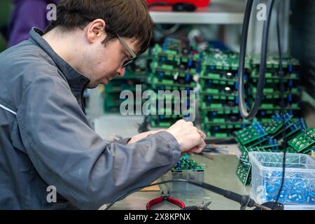 Perm, Russia - May 23, 2024: worker assembling electronic equipment in a workshop Stock Photo
