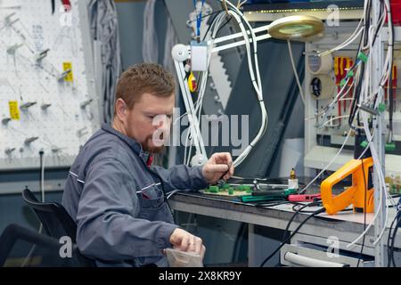Perm, Russia - May 23, 2024: worker assembling electrical equipment in a workshop Stock Photo