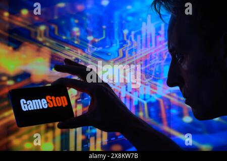 Brussels, Belgium. 25th May, 2024. GameStop logo is displayed on a smartphone with stock graph visible on screen in the background in this photo illustration. Taken in Brussels, Belgium. On May 25, 2024. (Jonathan Raa/Sipa USA) *** Strictly for editorial news purposes only *** Credit: Sipa USA/Alamy Live News Stock Photo