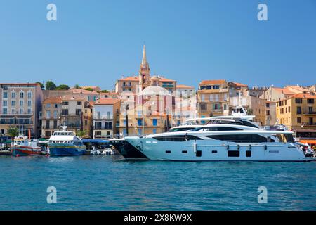 Calvi, Haute-Corse, Corsica, France. View across the marina, bell-tower of the Église Sainte-Marie Majeure prominent, luxury yachts moored at quay. Stock Photo