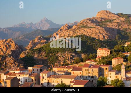 Piana, Corse-du-Sud, Corsica, France. View over village skyline to the high rocky landscape of the Calanques, sunset. Stock Photo