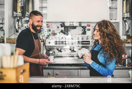 Two young baristas working in coffee shop, standing by counter. Teamwork. Stock Photo