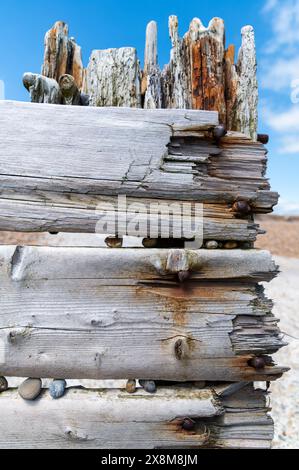 Ruined wooden sea defence planks near the Mary Stanford Lifeboat Station, Rye Harbour Nature Reserve with bleached timber and orange rusty bolts Stock Photo