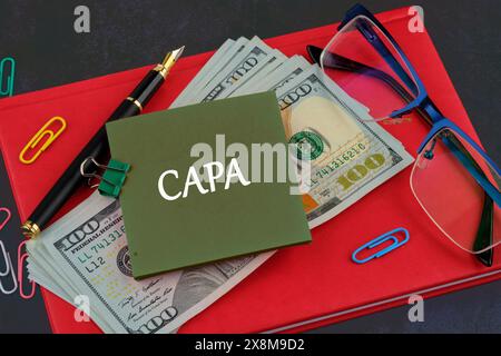 Words CAPA Corrective and Preventive action plans written on a sticker on the background of a business notebook and dollars Stock Photo