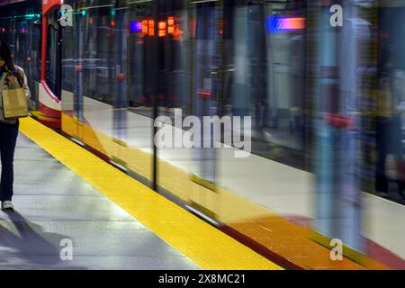Female at a downtown light rail transit station at night in Calgary, Alberta Canada Stock Photo