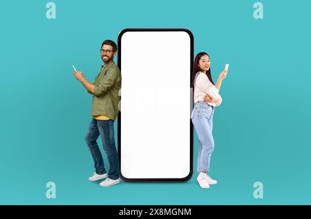 Man and Woman Standing Next to Blank Screen on Blue Stock Photo