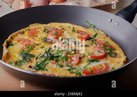 Fresh mushroom and tomato omelette resting in a frying pan. Stock Photo