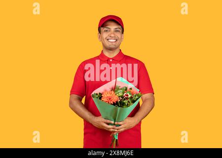 Smiling Delivery Person Holding Colorful Flower Bouquet Against Bright Yellow Stock Photo