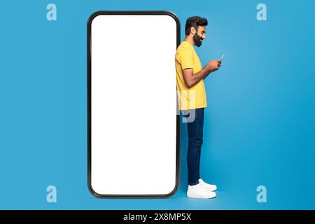 Young Man Using Smartphone Against Giant Phone Frame Stock Photo