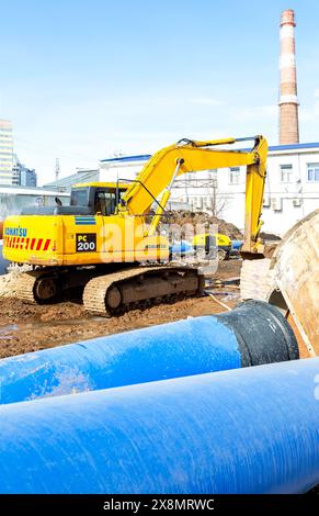 Samara, Russia - March 17, 2024: An excavator is working on a construction site to lay large diameter pipes in a trench Stock Photo