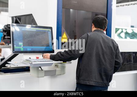 The operator operates an automatic machine for cutting metal. Smart factory. Stock Photo