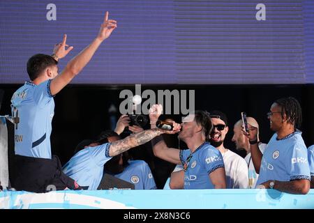 Manchester City's Jack Grealish (centre) takes a drink from Kyle Walker during a trophy parade in Manchester, after they won their fourth successive Premier League title and their sixth in seven years. Picture date: Sunday May 26, 2024. Stock Photo