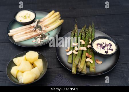 White and green asparagus served on dark plates with hollandaise sauce. Asparagus representing dietary fiber is very popular in Germany during Spargel Stock Photo