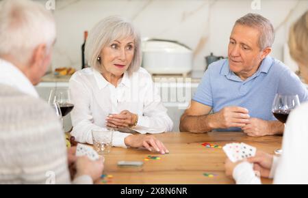 Group of friends playing poker cards and drinking wine at home Stock Photo