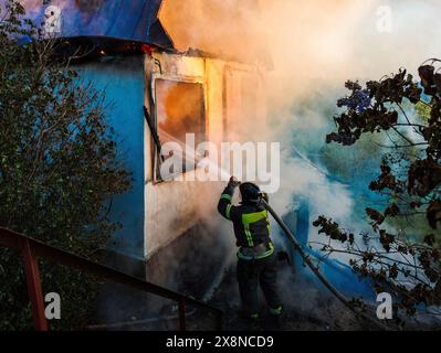Firefighter extinguish fire in house using spraying hose. Stock Photo