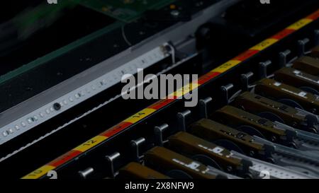 Close up of details of automatic SMD pick and place machine during work. Creative. Assembly of computer printed circuit board at factory. Stock Photo