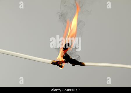 Electrical wire burning on light background, closeup Stock Photo