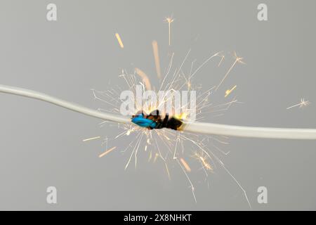 Sparking electrical wire on light background, closeup Stock Photo