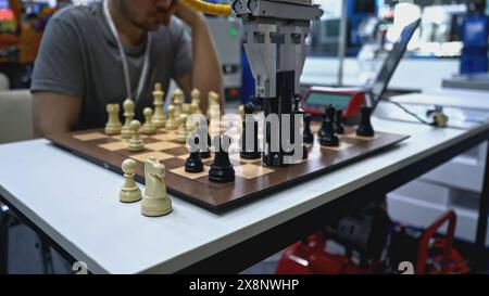 Man is playing chess with robot. Media. Man is playing chess against robot at exhibition. Artificial intelligence technologies versus humans Stock Photo