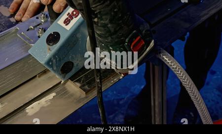 A worker saws ceramic tiles with a grinder. Creative. Cutting ceramics with machine and water to avoid dust. Stock Photo