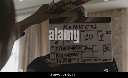 Man with clapperboard on set of movie. Stock. Man slaps clapperboard at beginning of movie shoot. Backstage with man and clapperboard before actors Stock Photo